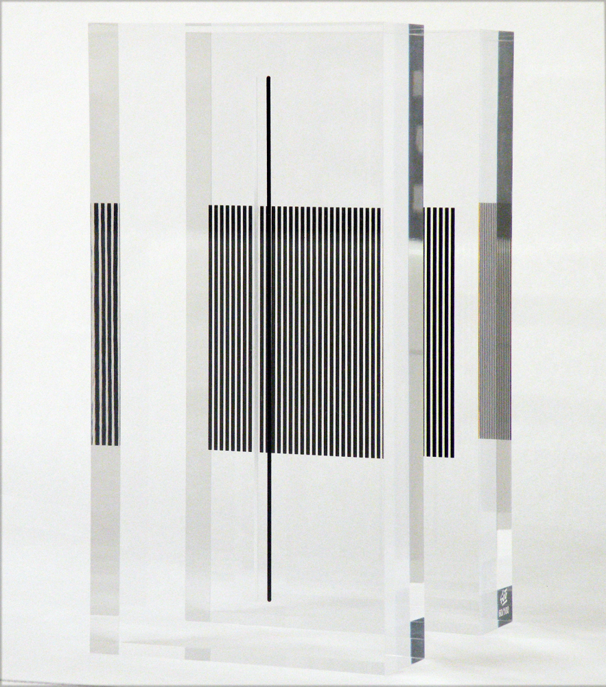 This plexiglass structure exemplifies the ways in which Soto experimented with the idea of plane superposition: two blocks of the material, upon which reticules and a singular line that serves as center or visual guide can be appreciated, create a diversity of optical effects that play with perception beyond bidimensionality. The transparent mass recalls the immersion in the very space in which spectators are, situating their movement as the central element gives the work of art its finishing touch, in a sense.